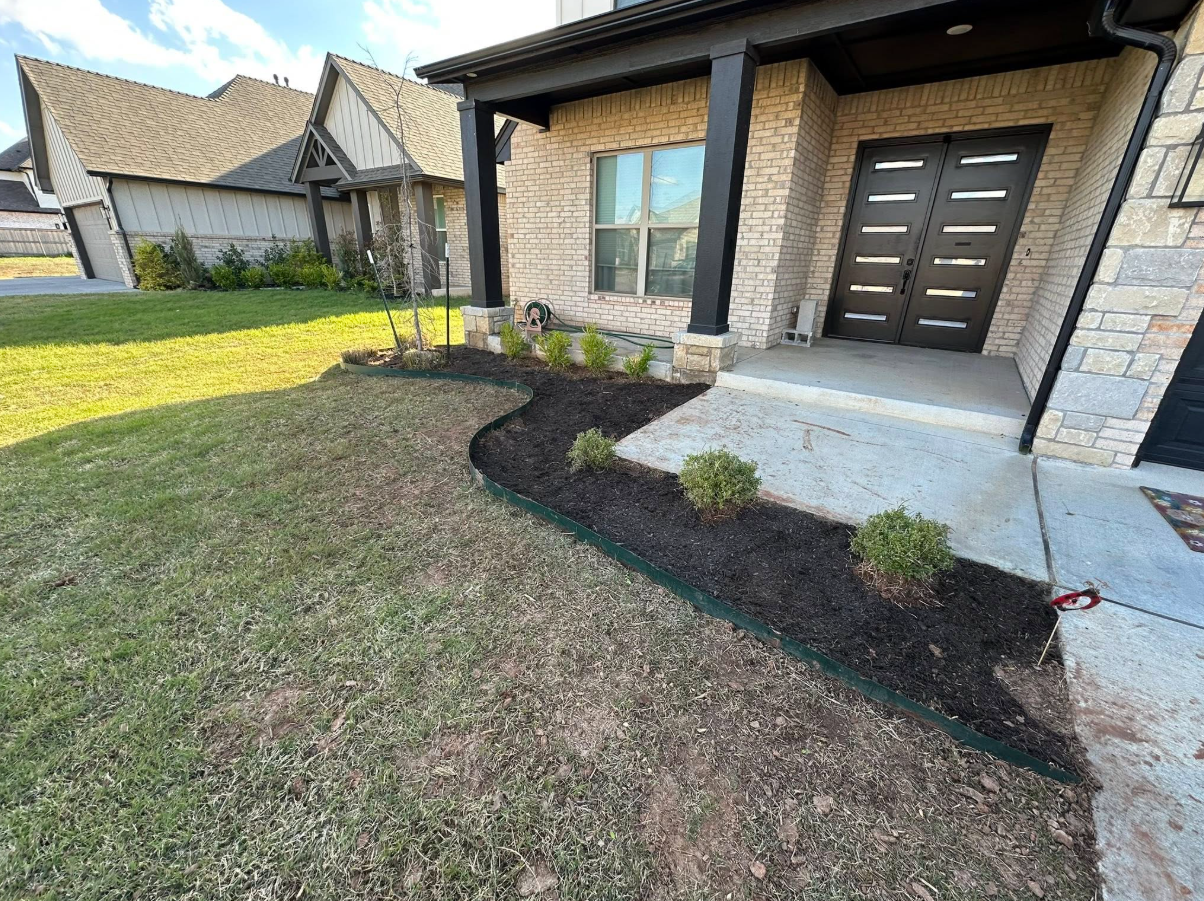 Side of a house with fresh mulch beds and manicured turf